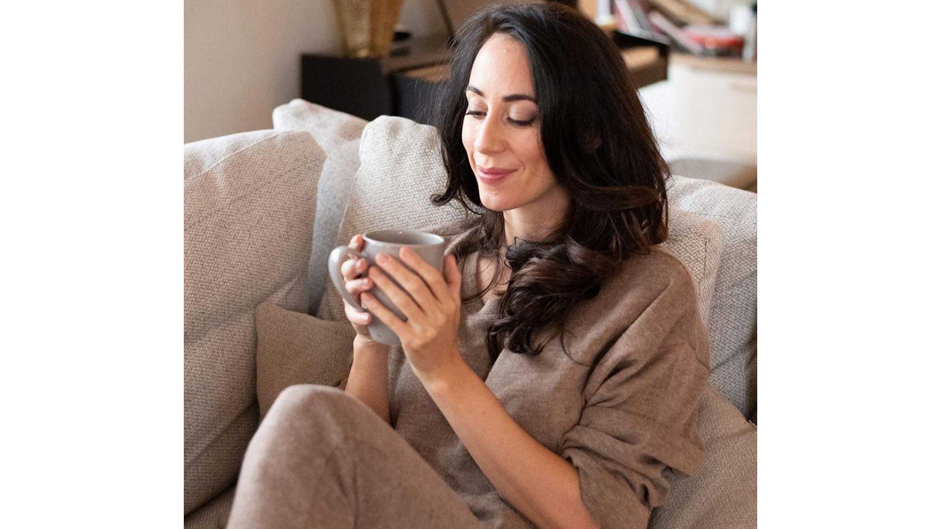 jamieheringer_sitzt_auf_Sofa_mit_Tasse_in_ihren_Haenden