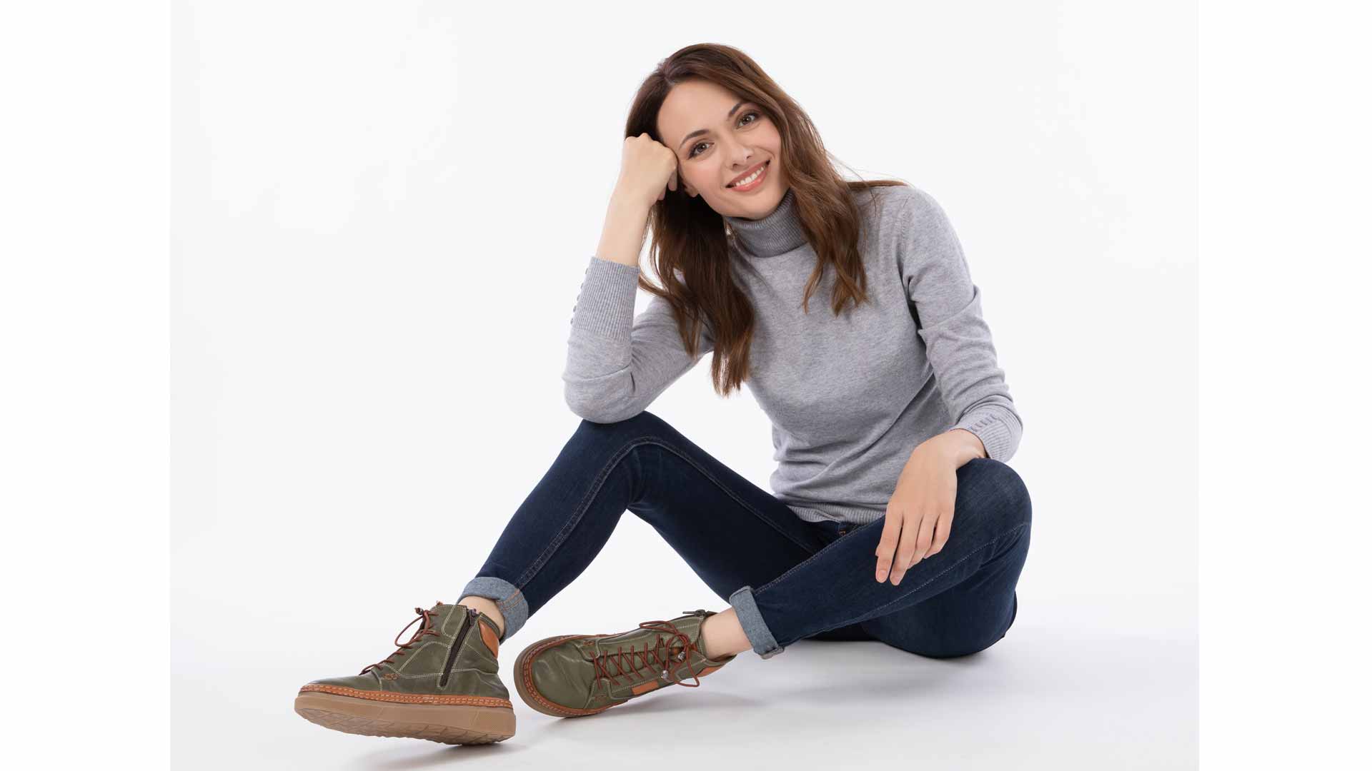 coverbild model_sitzt_graues_shirt_blauehose_grüne_schuhe